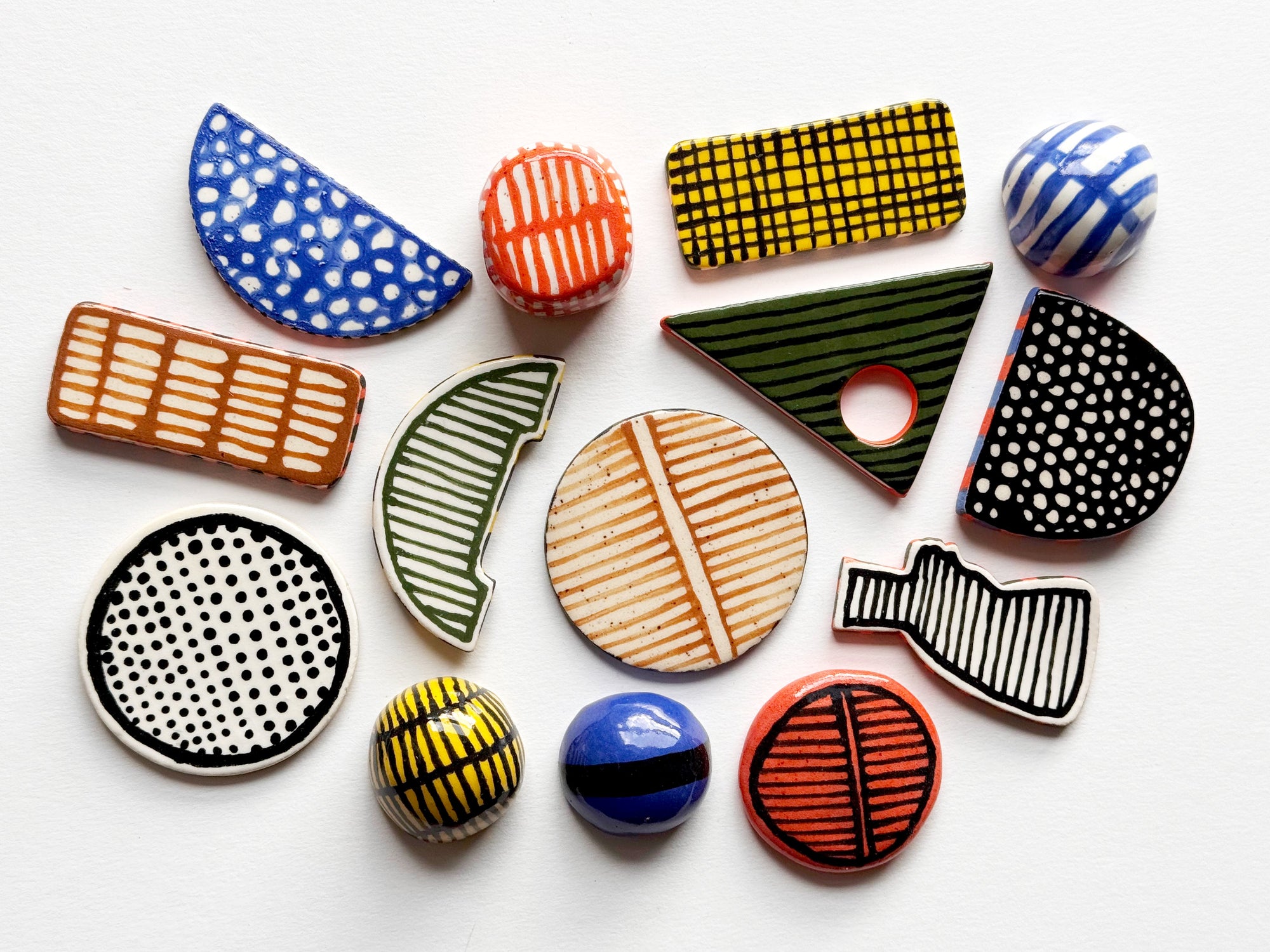 A collection of colorful, hand-painted wooden beads with various geometric shapes and patterns, arranged on a plain white background.
